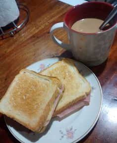 a sandwich on a plate next to a cup of coffee and a mug of tea
