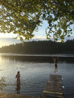 two people jumping into the water from a dock