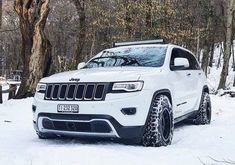 a white jeep is parked in the snow