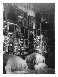 an old black and white photo of two beds in a room with many pictures on the wall