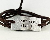 a brown leather bracelet with a silver plate that says proud army sister