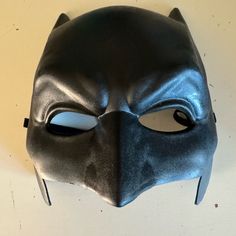 a batman mask is shown on a white surface with black eyes and nose ring,