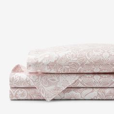 the pink and white sheets are folded on top of each other, with an intricate pattern