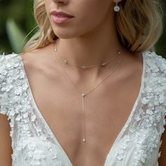 a woman in a white dress wearing a necklace and earring on her left side