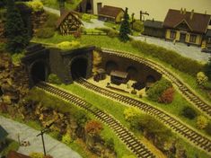 a model train set is shown with buildings and trees on the side of the track
