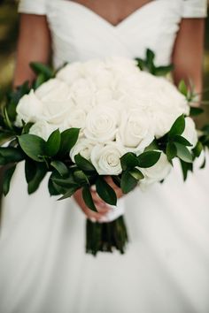 a bride holding a bouquet of white roses