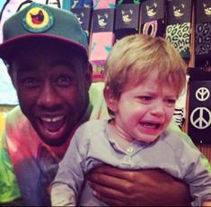 a man holding a small child in his arms and smiling at the camera with peace signs behind him