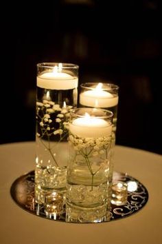 candles are lit on a table with glass vases