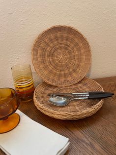 two wicker plates and one glass on a wooden table