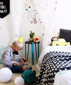 a young boy sitting on the floor playing with toys in his child's bedroom