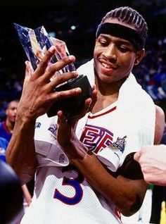 the basketball player is holding his trophy in one hand and looking down at it while standing next to an audience