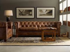 a brown leather couch sitting in a living room next to a table and lamp on top of a rug