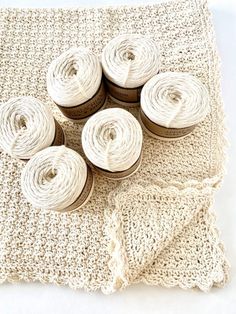 four spools of thread sitting on top of a white crocheted blanket