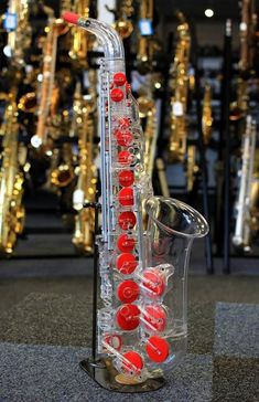 a saxophone with red buttons on it in front of many other musical instrument cases and gold - plated objects