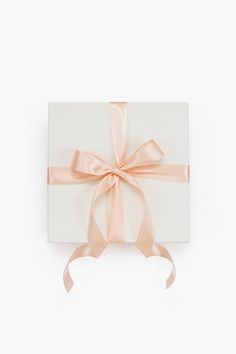 a white box with a pink ribbon tied around the bow on it's side