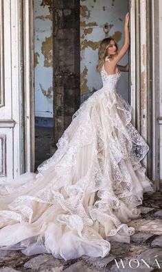 a woman in a wedding dress is standing by an open door with her arms up