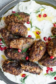 some meatballs are in a bowl with yogurt and pomegranate