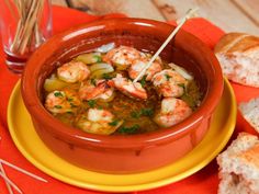 a bowl of soup with shrimp and bread on the side