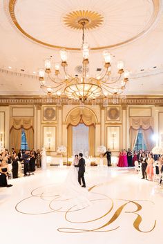 a bride and groom are standing in the middle of an ornate ballroom with chandeliers
