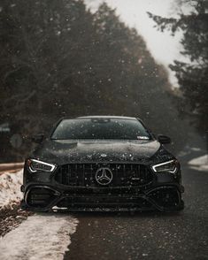 the front end of a black mercedes cla on a snowy road