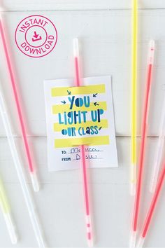 four colored straws sitting on top of a white table next to a card with the words you light up our class