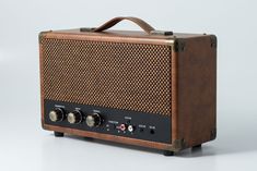 an old fashioned radio sitting on top of a white table next to a black and brown speaker