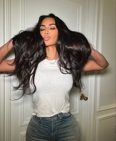 a woman with long hair standing in front of a door