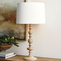 a wooden table with a lamp on it next to a potted plant and books