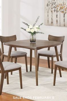 a dining table with four chairs and a vase filled with flowers on top of it