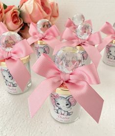 four small jars with pink bows and crystal balls in the top one has an elephant on it