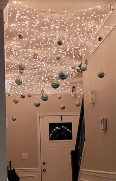 an entry way decorated with christmas lights and baubles hanging from the ceiling above it