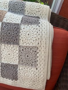 a crocheted blanket sitting on top of a couch next to a potted plant