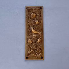 a decorative metal plaque with birds and flowers on it's side, mounted on a wall