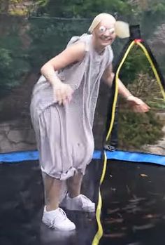 a woman in a gray dress is on a trampoline