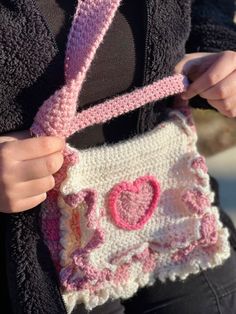 a woman is holding a crocheted purse with hearts on the front and sides