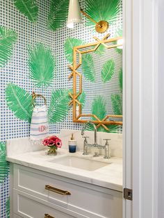 a bathroom with palm leaves on the wall and sink in the foreground is a mirror