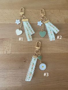 four key chains with flowers and hearts attached to them on a wooden surface, showing the number one