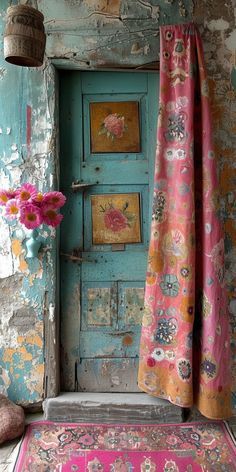 an old door is painted blue and has pink flowers on the rug next to it