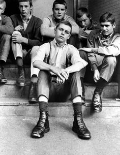 black and white photograph of boys sitting on steps with their legs crossed in front of them