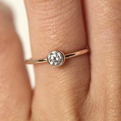 a woman's hand with a diamond ring on top of her finger, showing the center stone