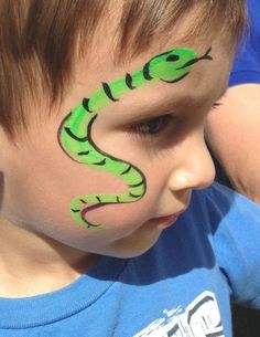 a young boy with his face painted like a green snake on it's cheek