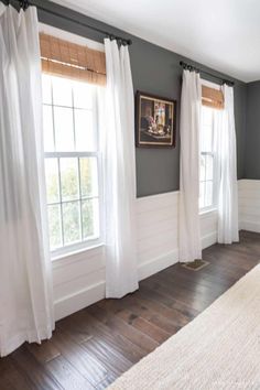 a bedroom with gray walls, white curtains and wood floors is pictured in this image