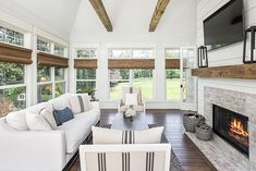 a living room filled with furniture and a flat screen tv mounted on the wall above a fire place