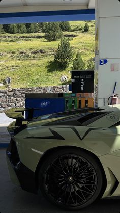 a green sports car parked at a gas station