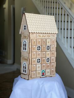 a house made out of cardboard sitting on top of a white cloth covered tablecloth