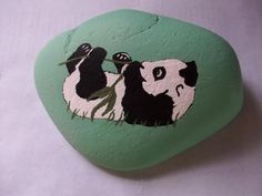 a painted rock with two panda bears on it