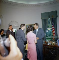 a group of people standing in a room next to a table with an american flag on it