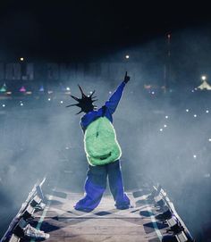 a person dressed as the statue of liberty standing on a stage with their arms in the air