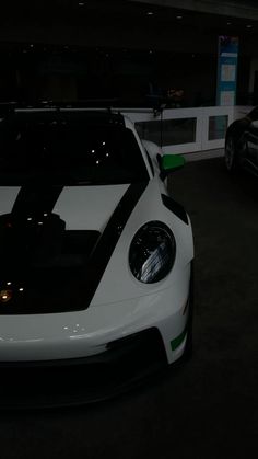 a white and black sports car parked in a parking lot next to other cars at night