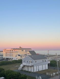 an ocean view with houses in the foreground and sunset on the horizon behind it